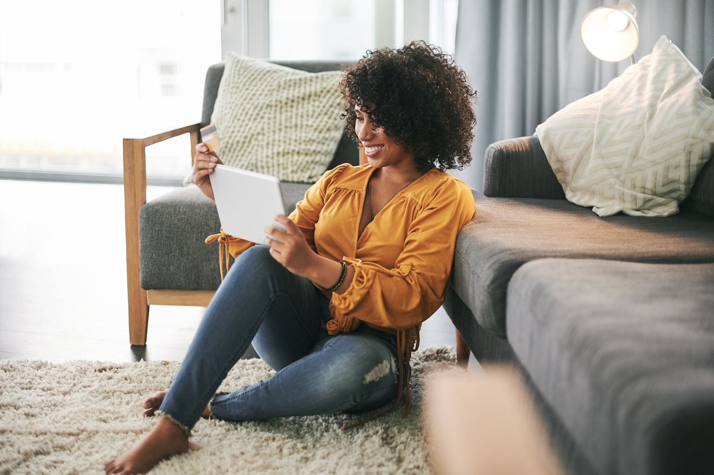 girl sitting on the floor with tablet holding a credit card